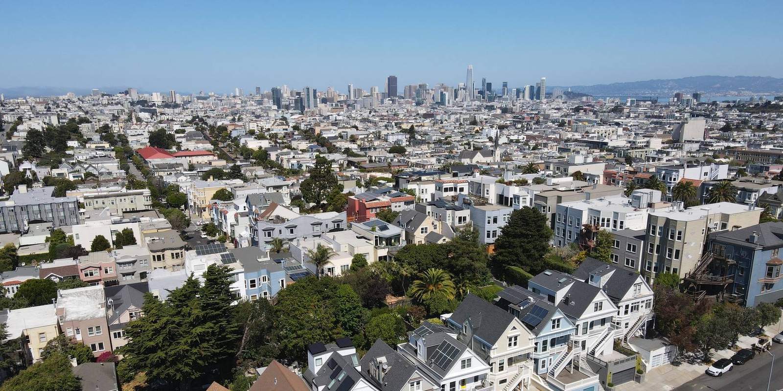 Aerial view across District 5 toward downtown San Francisco, with a row of Victorian homes in the foreground.