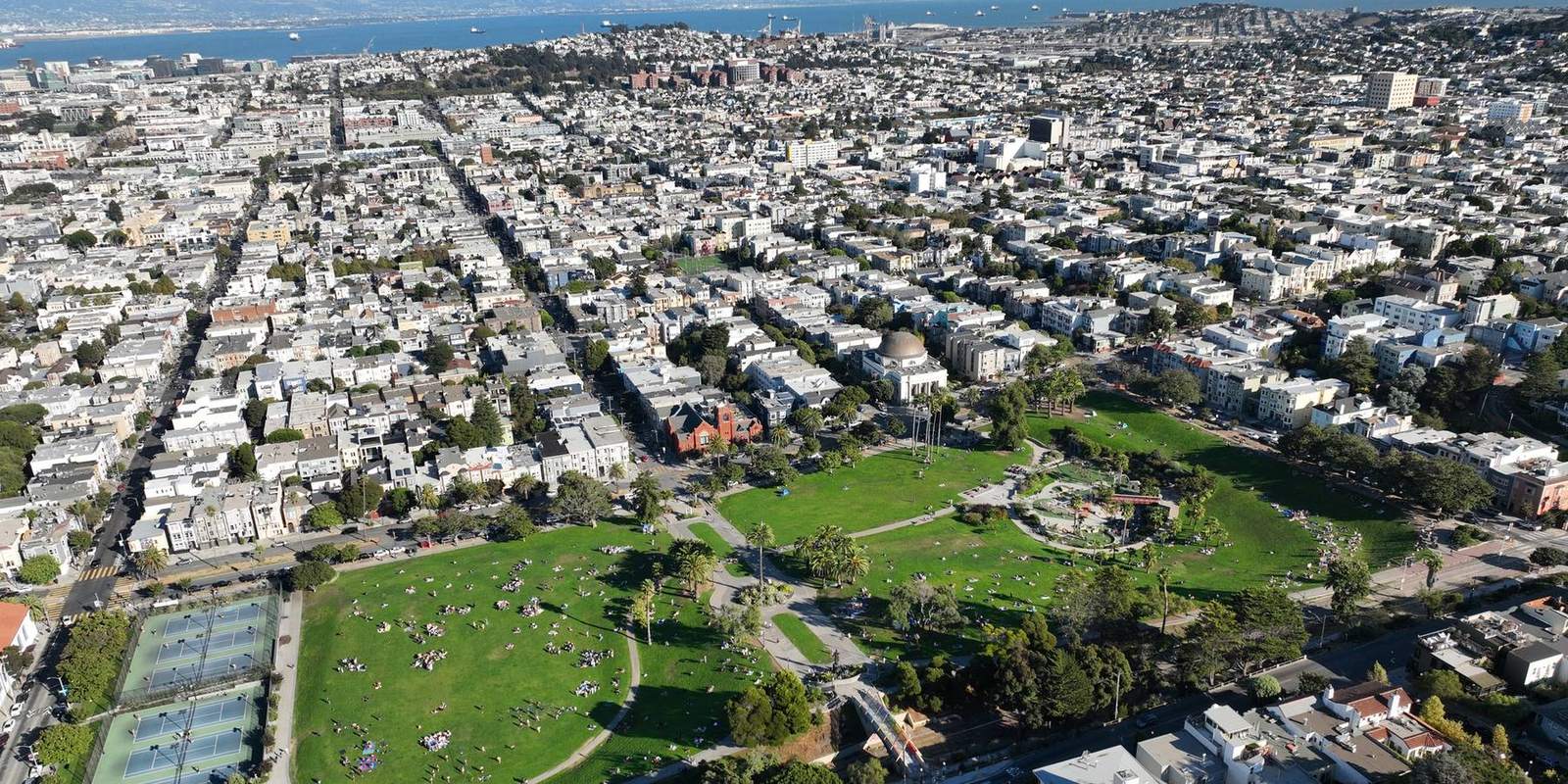 Aerial view of Dolores Park on a sunny afternoon, looking across the park and surrounding Mission and Dolores neighborhoods in San Francisco.