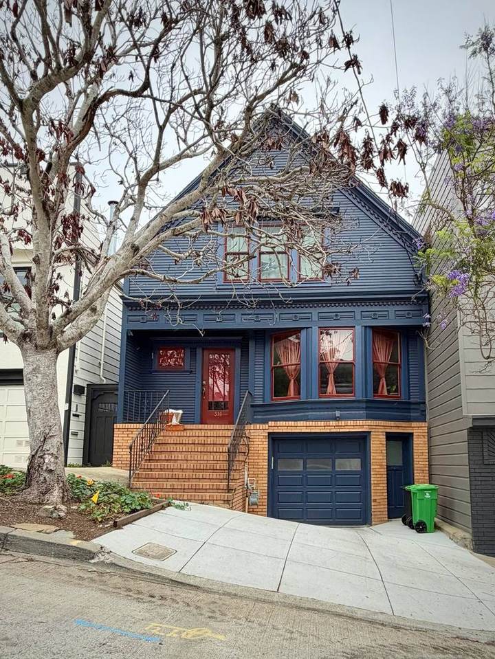 Navy clapboard cottage with brick-faced base