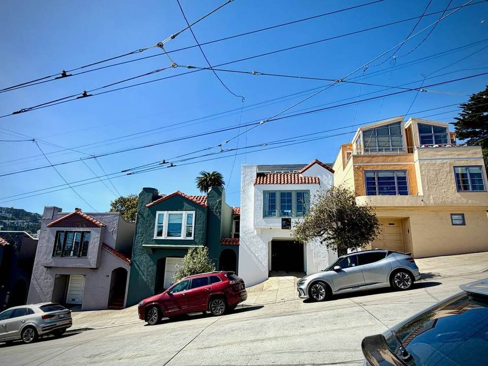 Stucco houses with tile roofs and garages beneath trolley wires