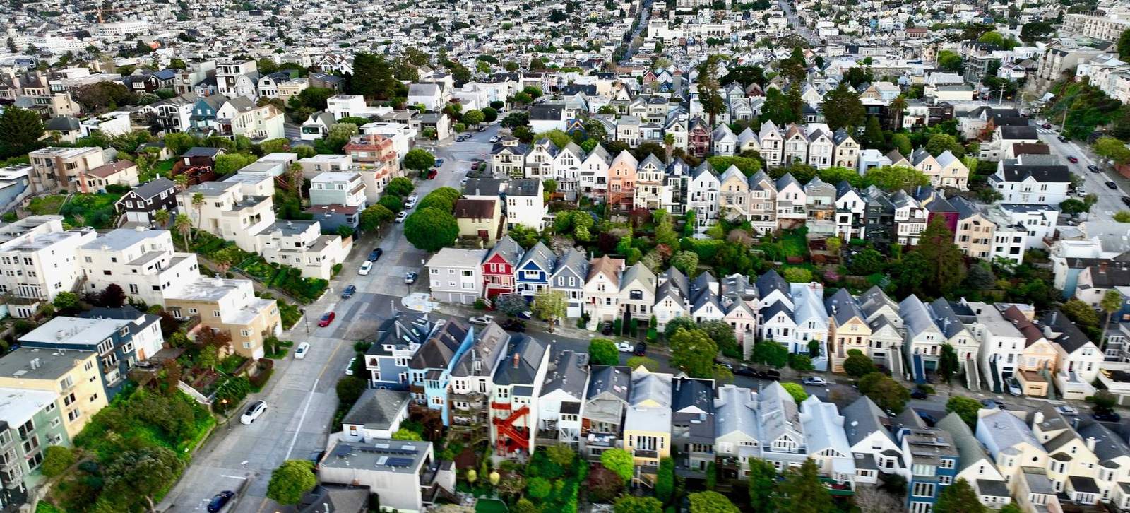 Aerial view at dusk over rows of District 5 Victorian houses, stepped rooflines and gardens